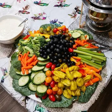 Colorful fresh vegetable platter with broccoli, peppers, tomatoes, and ranch dip